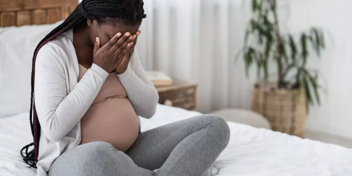 FeaturedImage-anxious-pregnant-woman-covering-face-bedroom.jpg