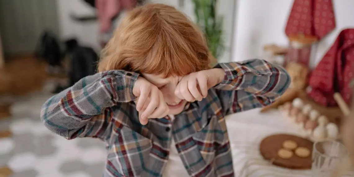 Overtired child rubbing eyes during play