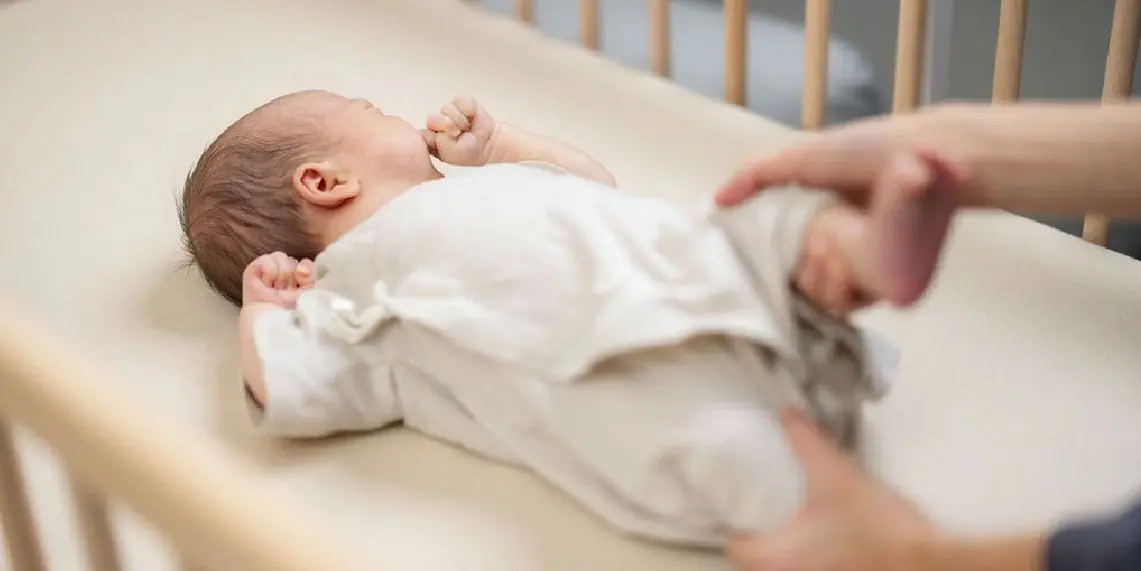 Newborn baby in crib with parent nearby showing early infant care and bowel movement monitoring