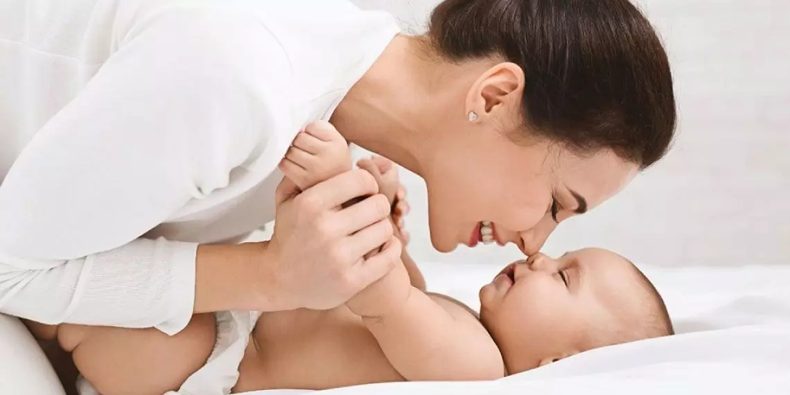 Mother smiling and playing with her baby