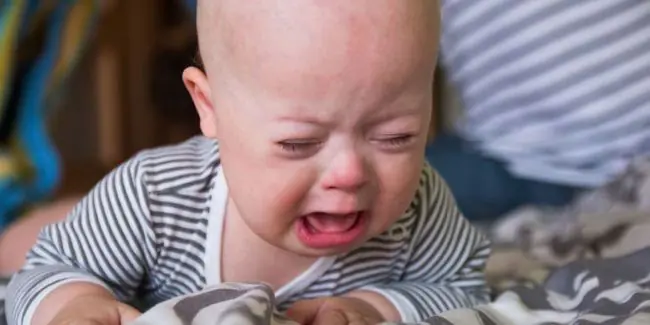 Fussy-baby-crying-during-tummy-time-with-parent-nearby-offering-comfort.jpg
